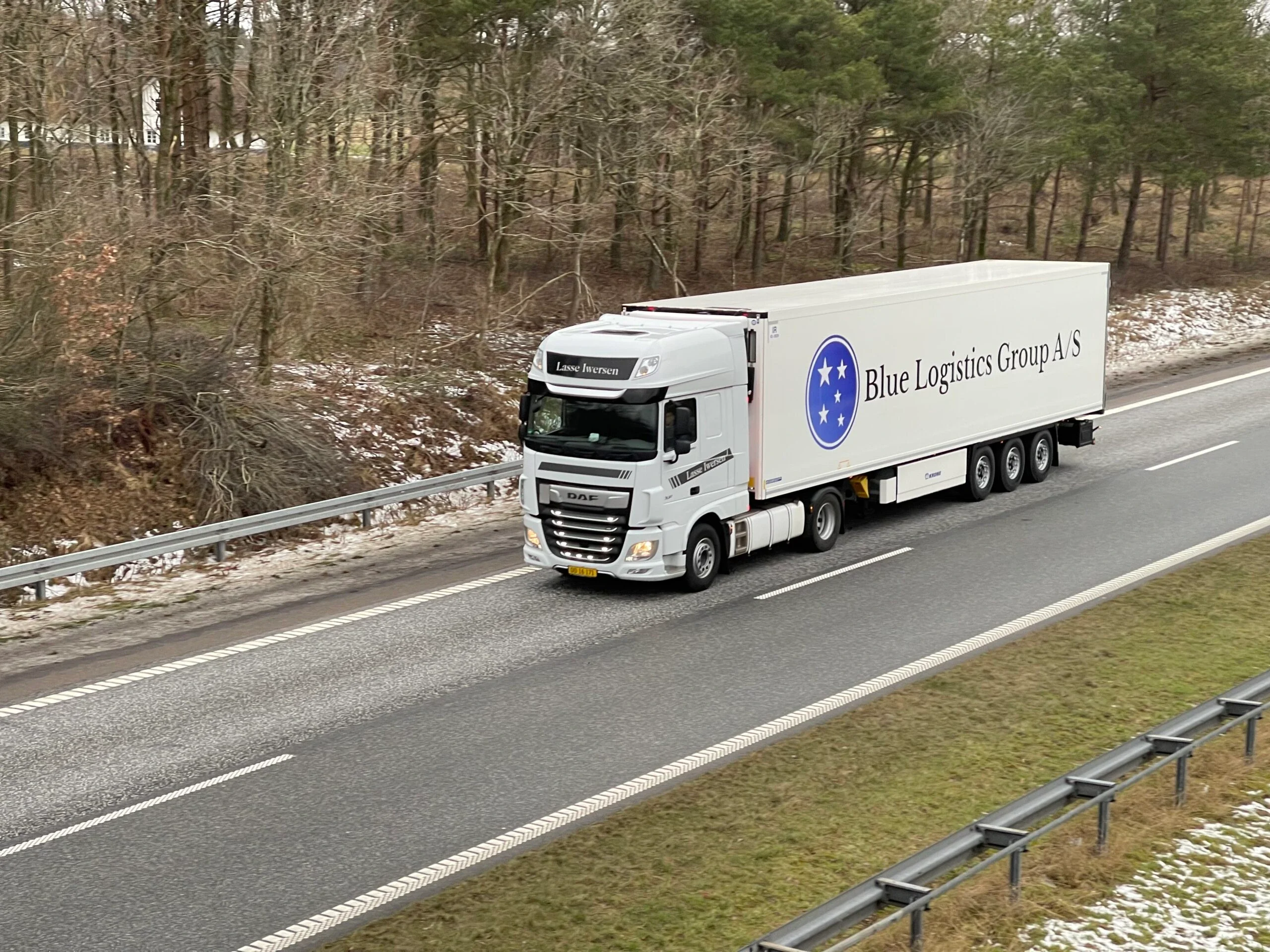 Lastbil med Blue Logistics Groups trailer på motorväg i vinterlandskap
