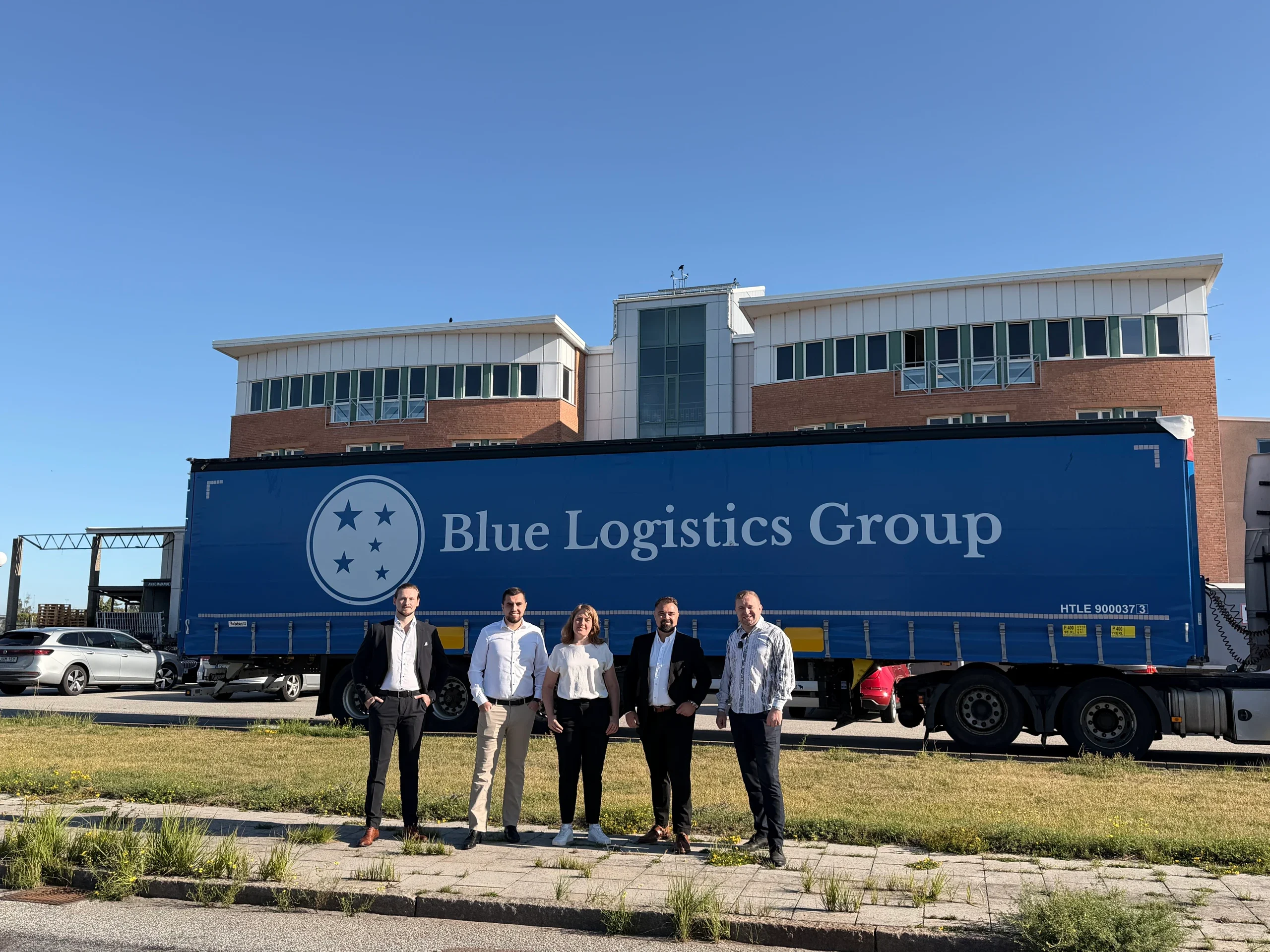 Medarbetare på Blue Log Continent Sweden framför en trailer med Blue Logistics Groups logotyp